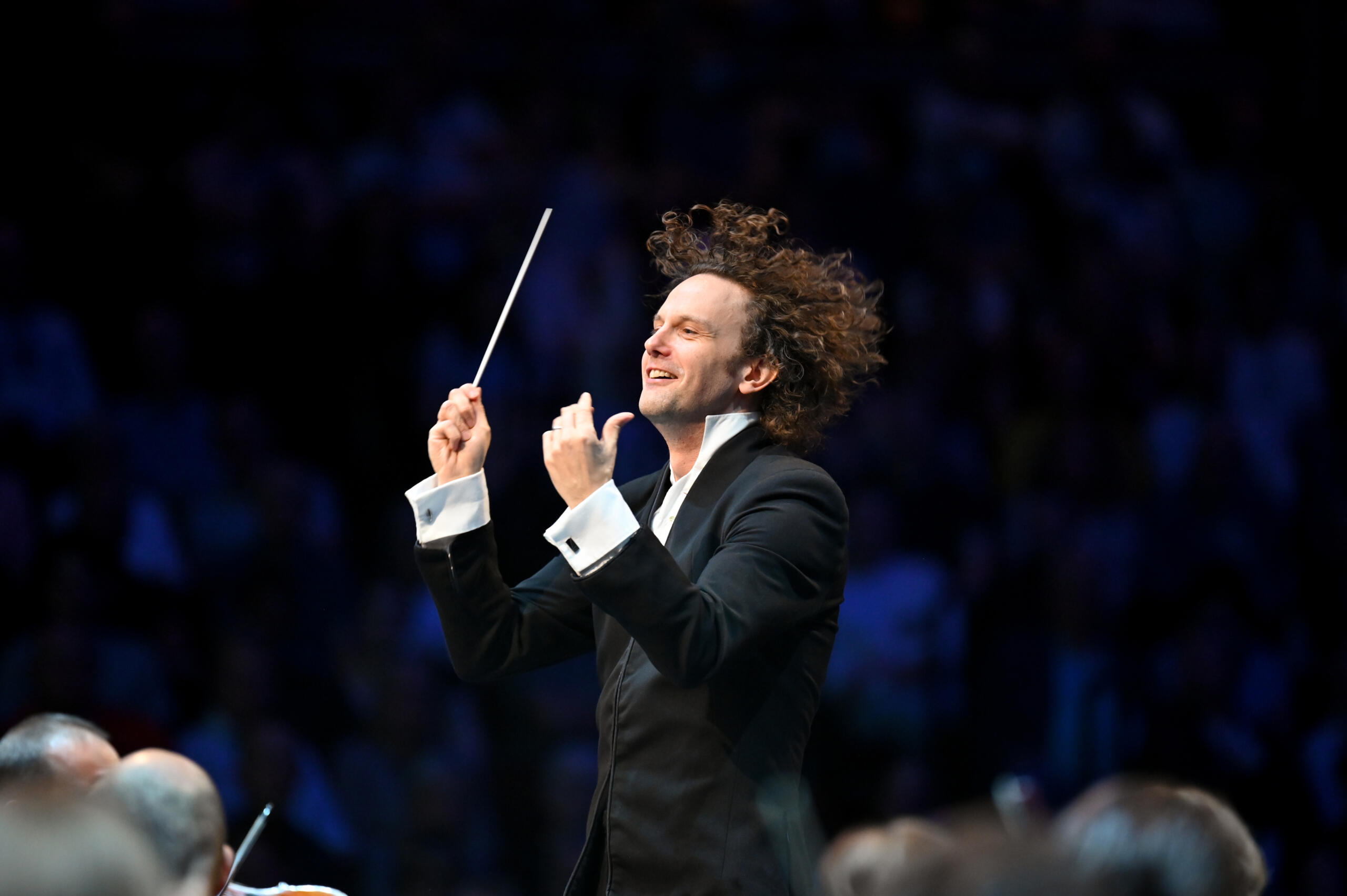 A conductor in action, his curls flying.