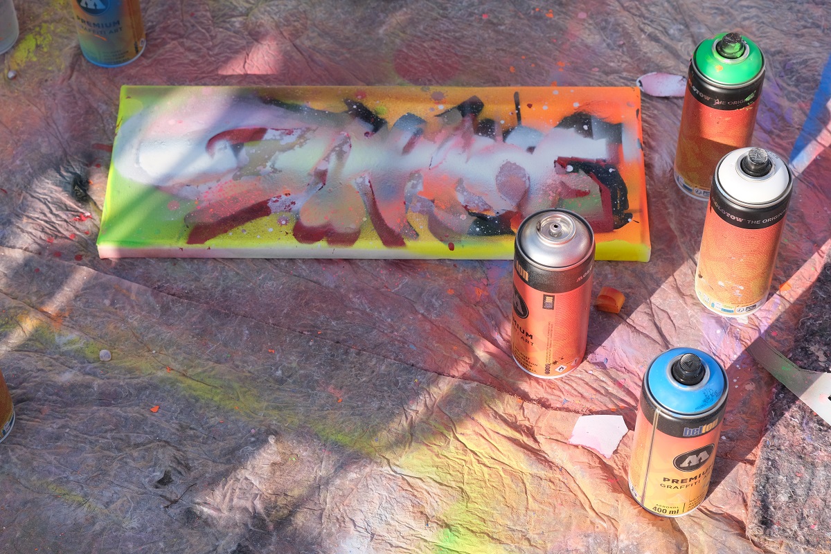 Tins of spray paint and a small sprayed canvas.