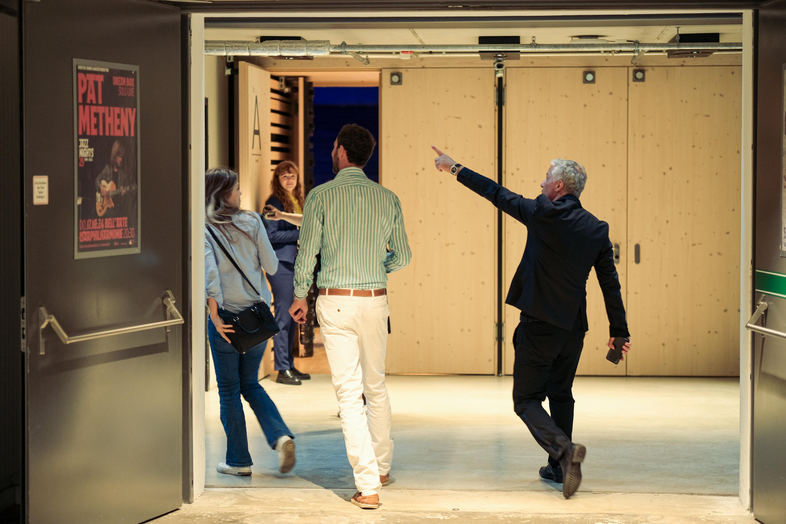 The entrance area of the concert hall, a man points the way for two people with an outstretched arm.