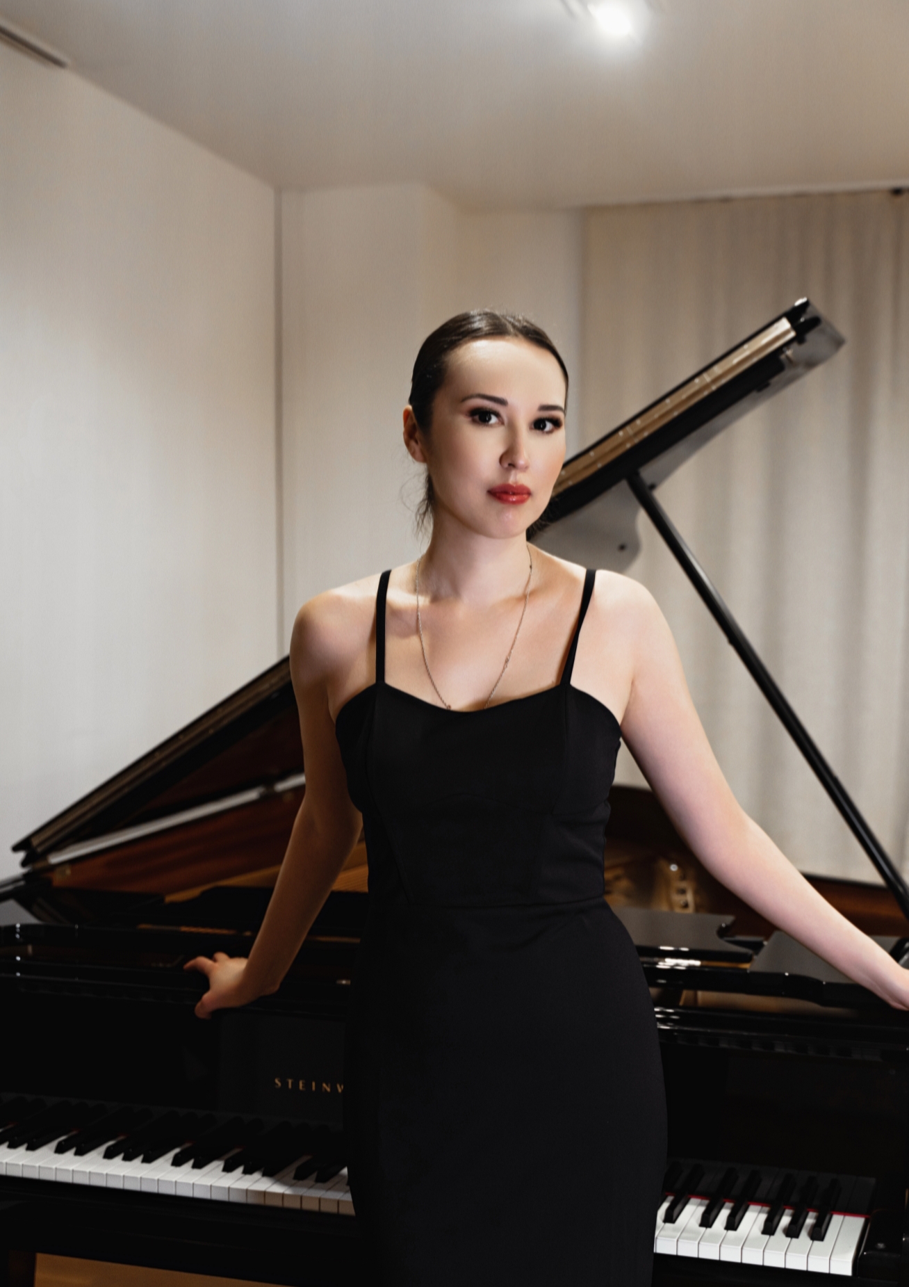 A young woman poses at a grand piano.