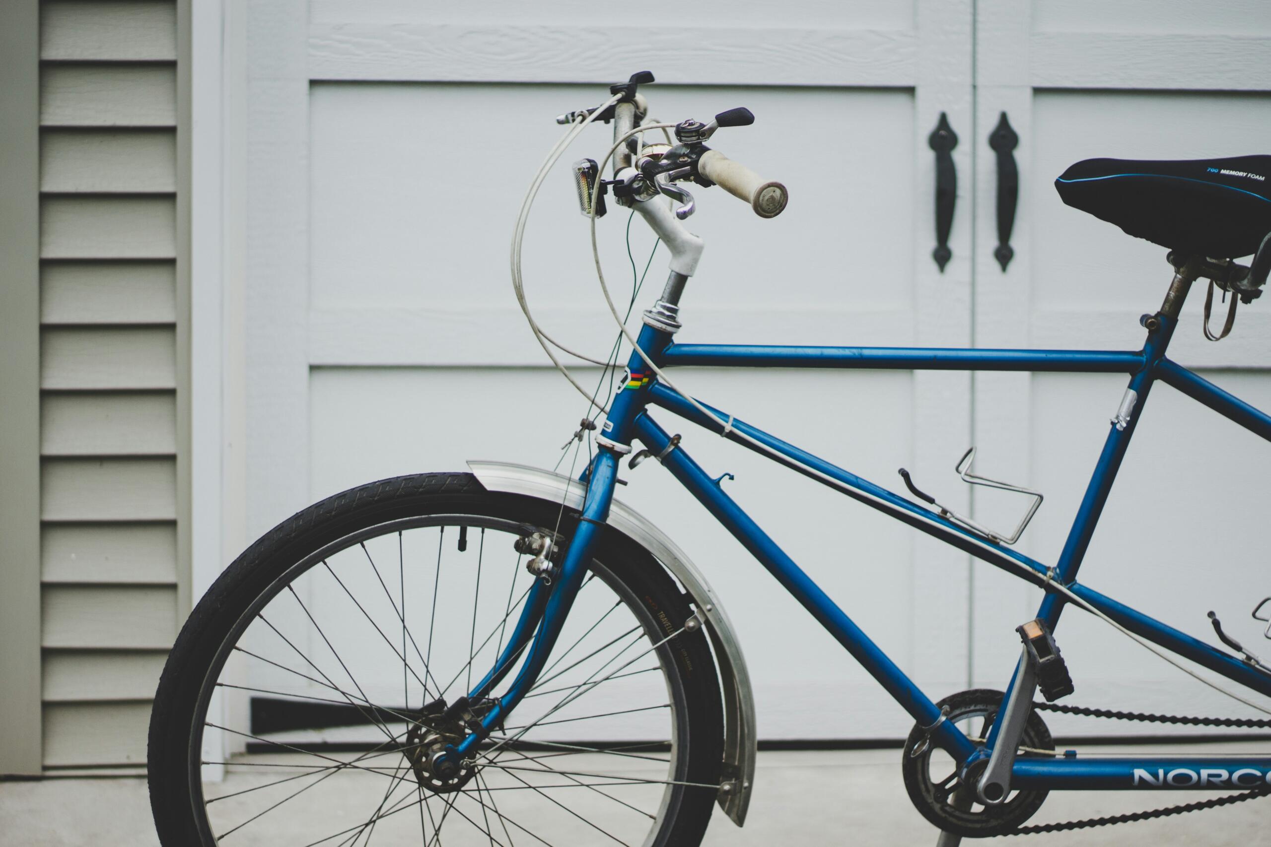 Ein blaues Fahrrad vor einem Holztor.